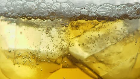 macro de una bebida de color whisky o cerveza gaseosa con hielo