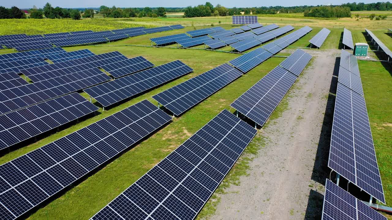 Ecological power station outdoors. Flying over the rows of blue solar panels on the field in summer. New source of electricity. Drone view.