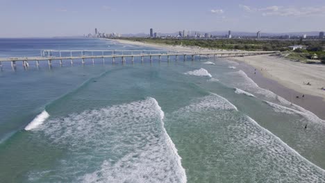 waves coming to the sandy strip of the spit gold coast - fishing pier and seawall