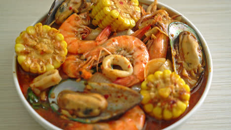 mariscos picantes a la barbacoa: gambas, calamares, mejillones y maíz.