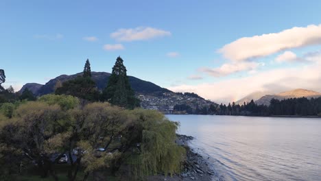 aerial footage captures queenstown's serene lake, lush greenery, and majestic mountains under soft, natural lighting