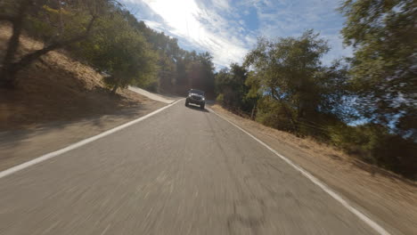 disparo de drone fpv de coche negro conduciendo rápido en la carretera