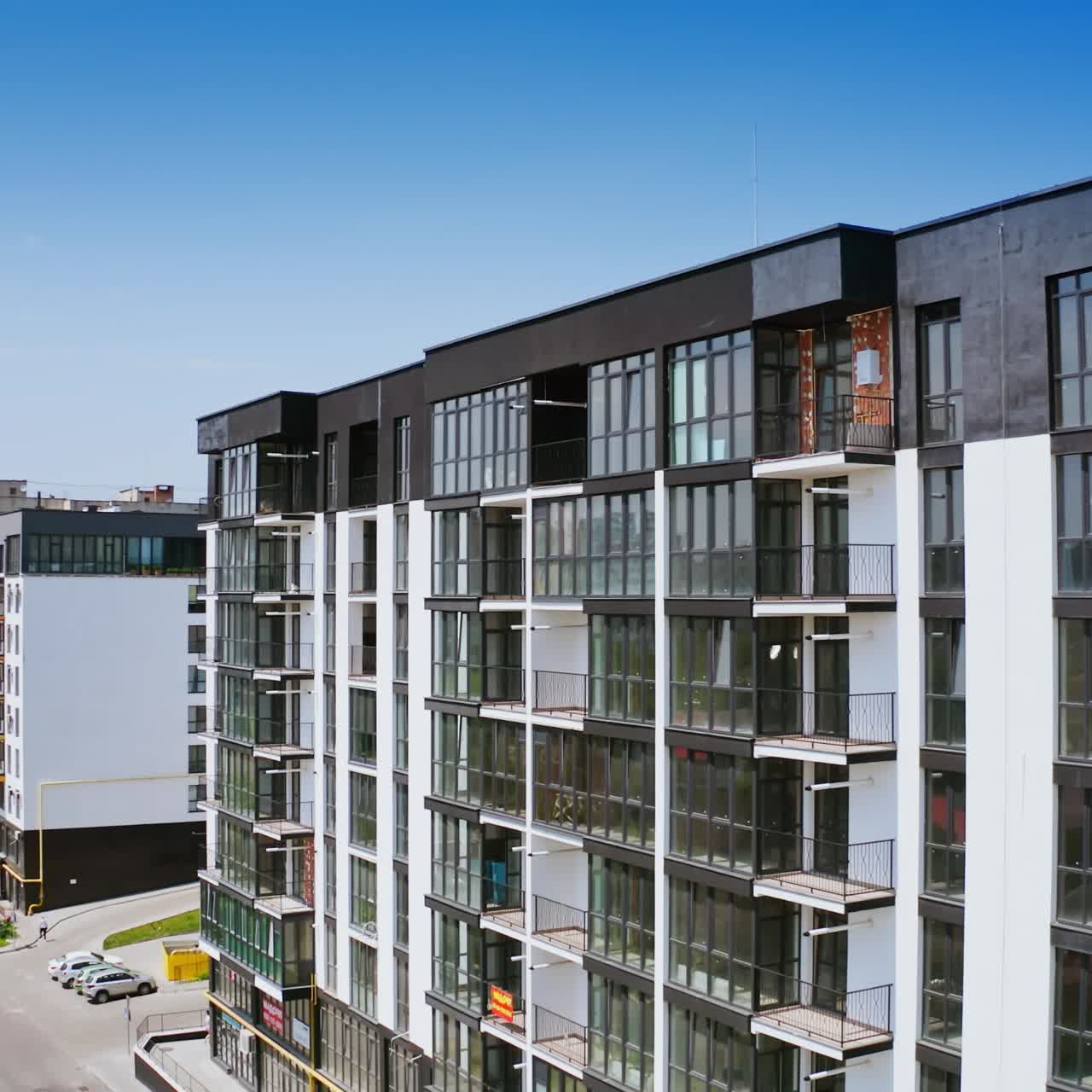 New highrise building in the city street. Modern design of newly built apartment building with large glassed balconies on urban background. View from the air
