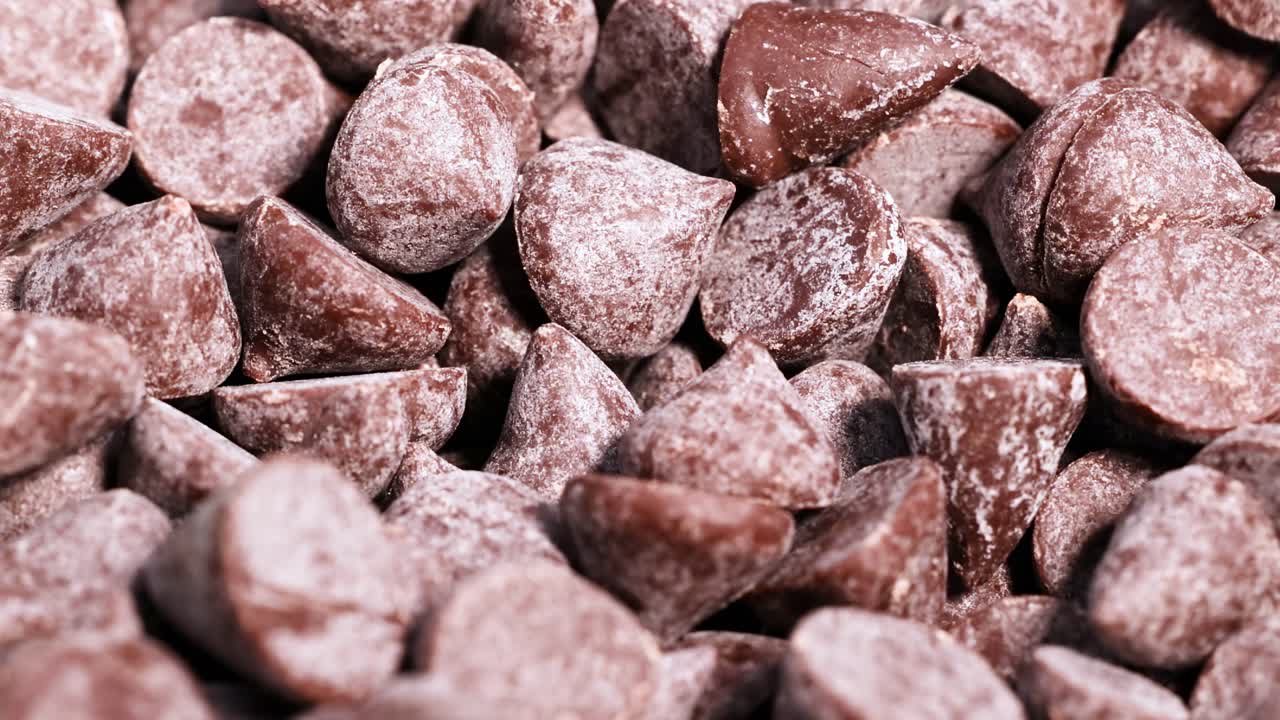 A detailed view of chocolate chips tumbling and settling into a dense pile.
