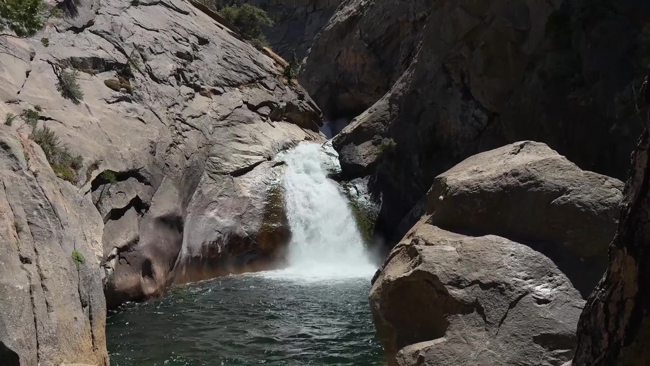 Un'inquadratura ampia di una cascata con rocce in primo piano.