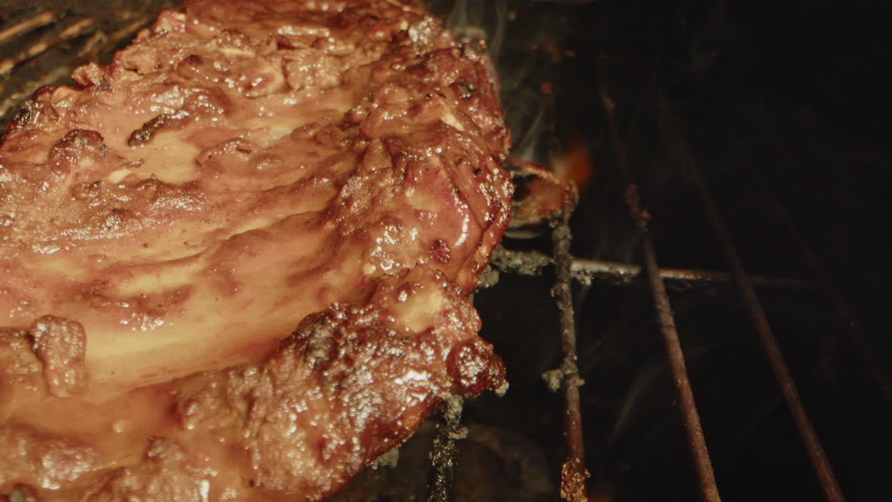 Close up of flames underneath a slab of spareribs being grilled on a barbecue