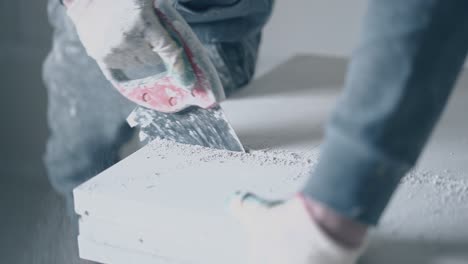 worker in gloves finishes sawing big white gypsum board