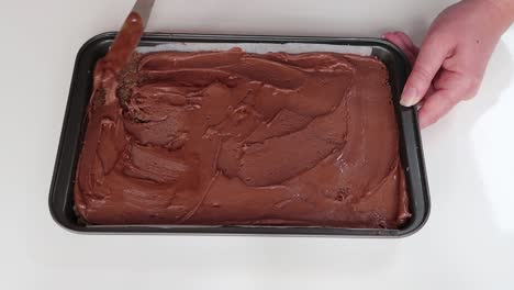 spreading chocolate icing on a slice
