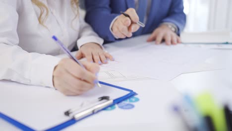 Man-and-woman-working-on-a-project-at-the-table.-Hands-in-close-up.