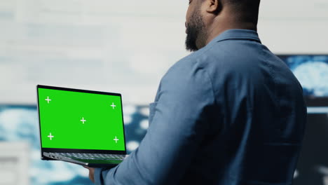 african american it specialist shows laptop with chroma key screen