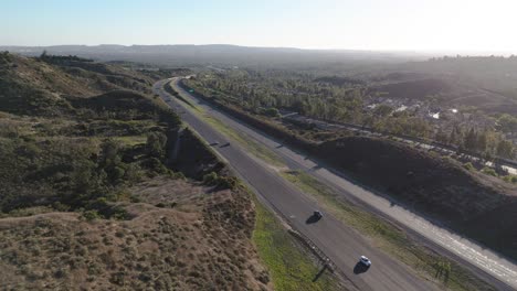 Viajando-Por-La-Autopista-Con-árboles-Altos-Y-Suburbios-En-La-Distancia