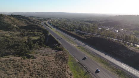 viajando por la autopista con árboles altos y suburbios en la distancia