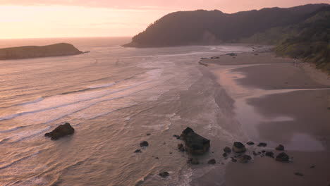 Drohne-Fliegt-Während-Eines-Stimmungsvollen-Und-Dunstigen-Sonnenuntergangs-Vorwärts-über-Einen-Wunderschönen-Strand-Mit-Meeresstapeln