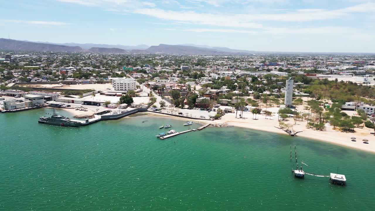 Beach view with umbrellas in La Paz, Playa Posada, calm water and city behind