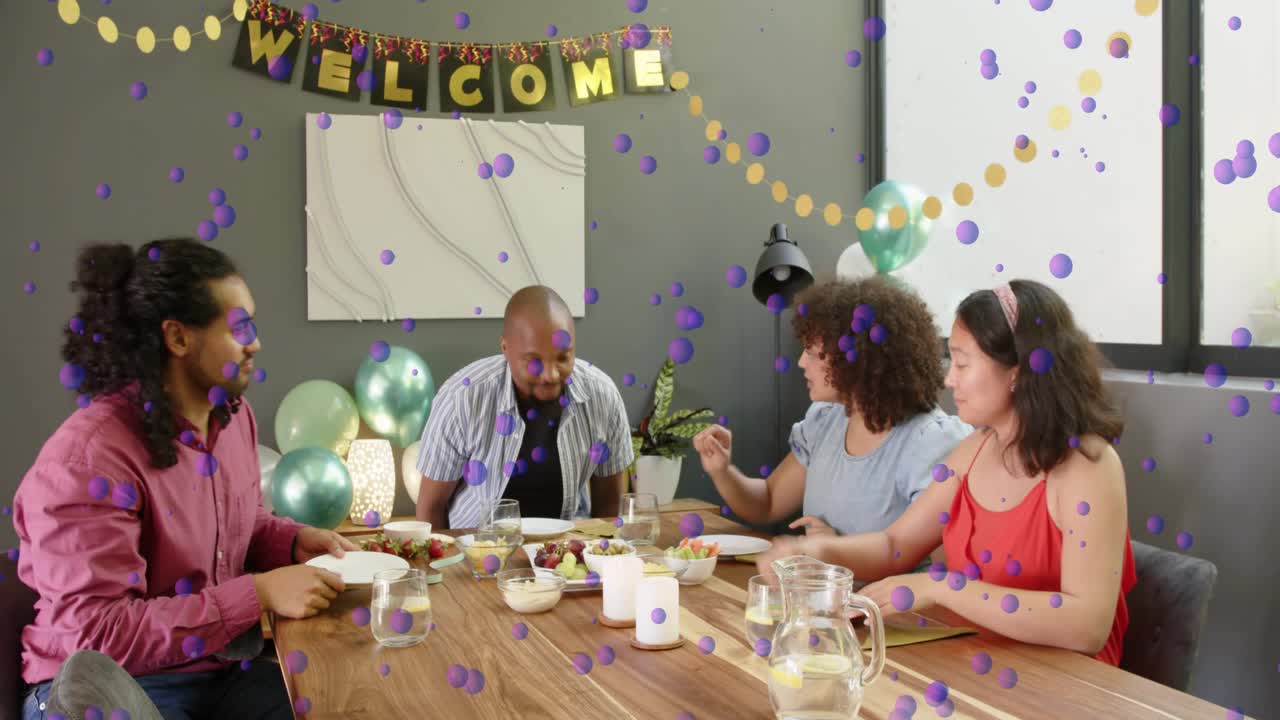 Server bringing platters, guests passing plates around wood table sharing welcome meal, purple dots
