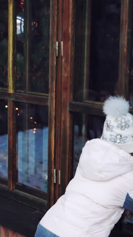 Child looking out of a window at Christmas lights