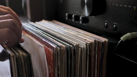 cerrar las manos del hombre hojeando discos de vinilo antiguos en casa