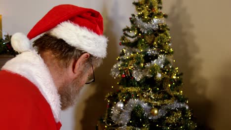 le père noël tient une liste et une boîte à cadeaux.