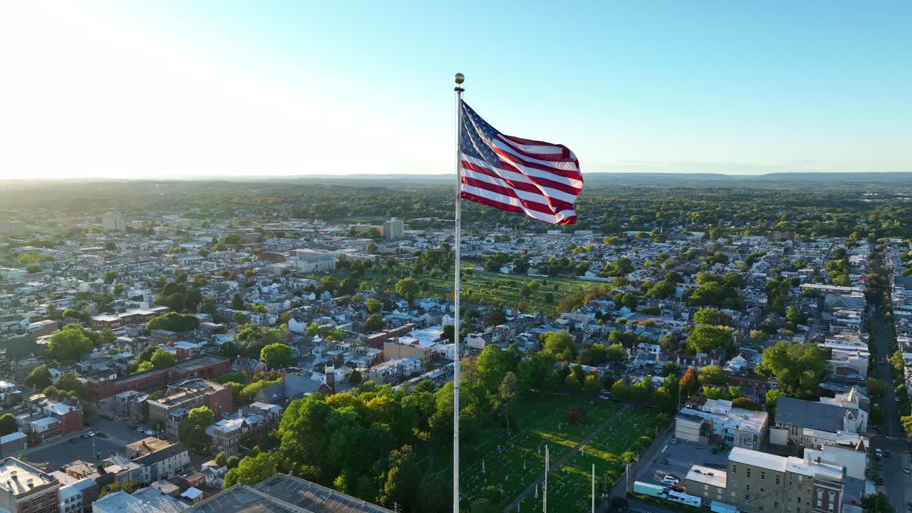 Bandiera americana sventola su una città americana con la luce del tramonto.