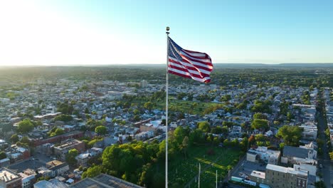 american flag waves over american city during sunset light