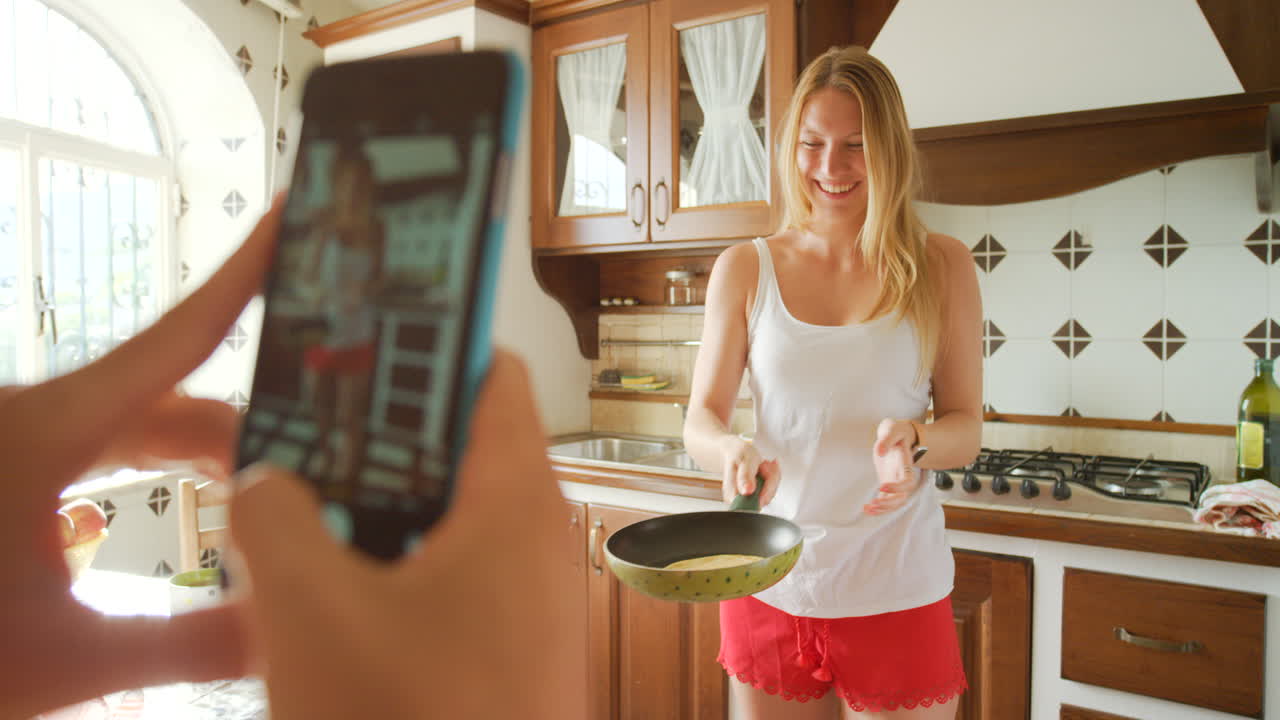 mujer feliz cocinando en la cocina siendo fotografiada