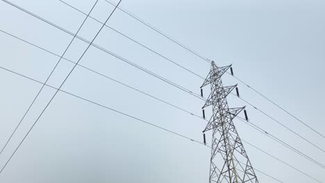 A-low-angle-shot-of-a-high-voltage-electricity-pylon-against-a-blue-sky,-depicting-the-power-and-infrastructure-of-modern-society