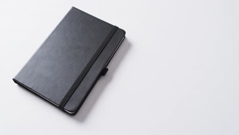 close up of closed black notebook with copy space on white background in slow motion