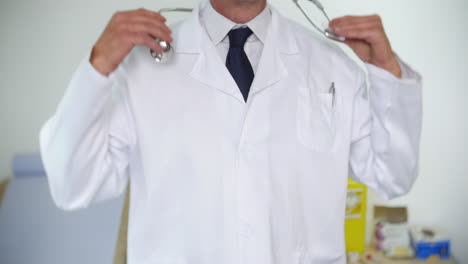 unrecognizable doctor in a white lab coat puts a stethoscope around his neck