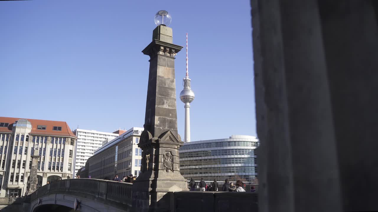 In the background you can see the most famous sight in Berlin, the Berlin television tower.
In the foreground many tourists and visitors walk over a beautiful bridge in beautiful summer weather.