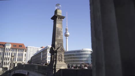 in the background you can see the most famous sight in berlin, the berlin television tower.
in the foreground many tourists and visitors walk over a beautiful bridge in beautiful summer weather.