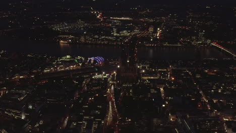 AERIAL:-Beautiful-Wide-Shot-over-Cologne-Germany-at-Night-time-with-City-lights