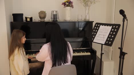 woman teaches girl piano bonding over music joy of learning and bond a heartwarming video shows a woman teaching a girl to play the piano with care bonding over music the joy of learning and bond between teacher and student are beautifully captured