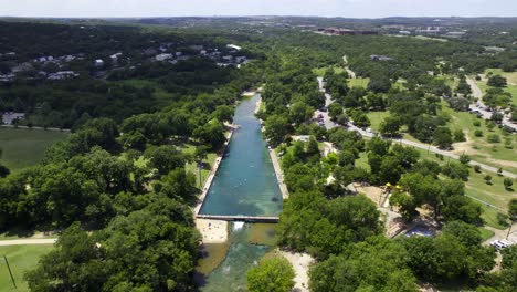 Vista-Aérea-Lejos-De-La-Piscina-Municipal-De-Barton-Springs,-Soleado,-Día-De-Verano-En-Austin,-Estados-Unidos:-Marcha-Atrás,-Inclinación,-Disparo-Con-Drones