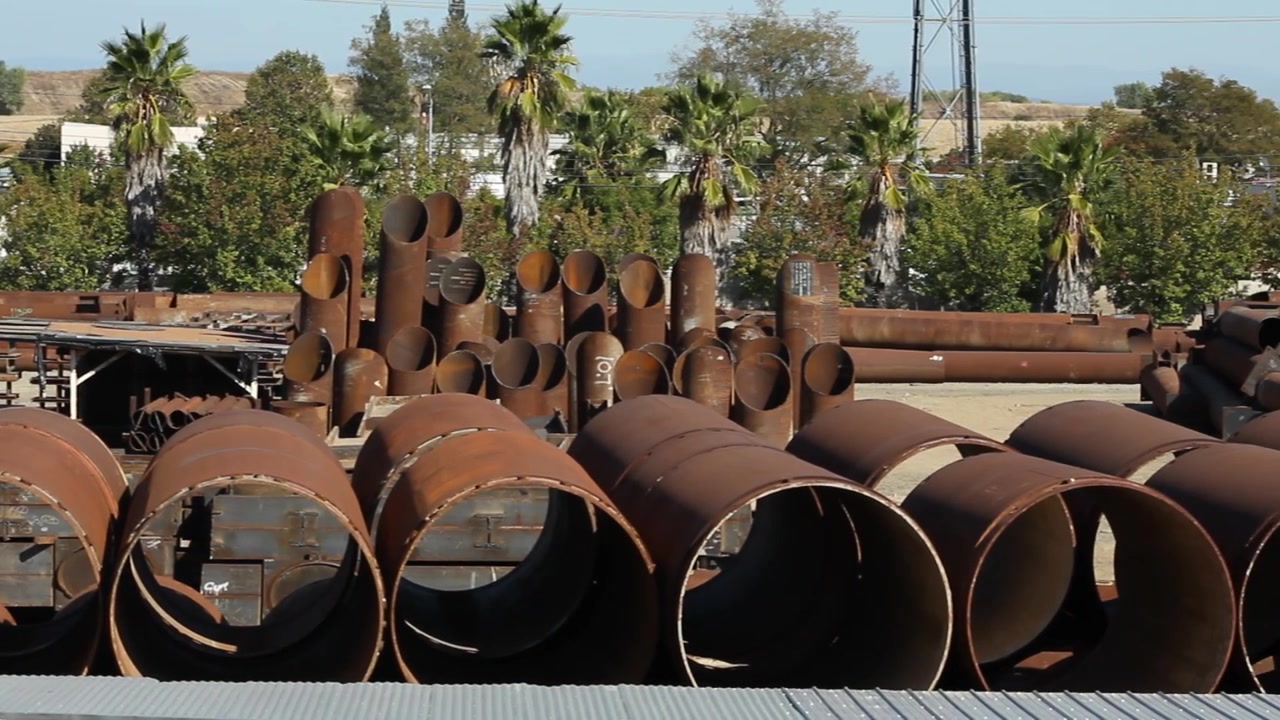 Grandi tubi industriali in acciaio arrugginito in un cantiere. Panoramica orizzontale da sinistra a destra.