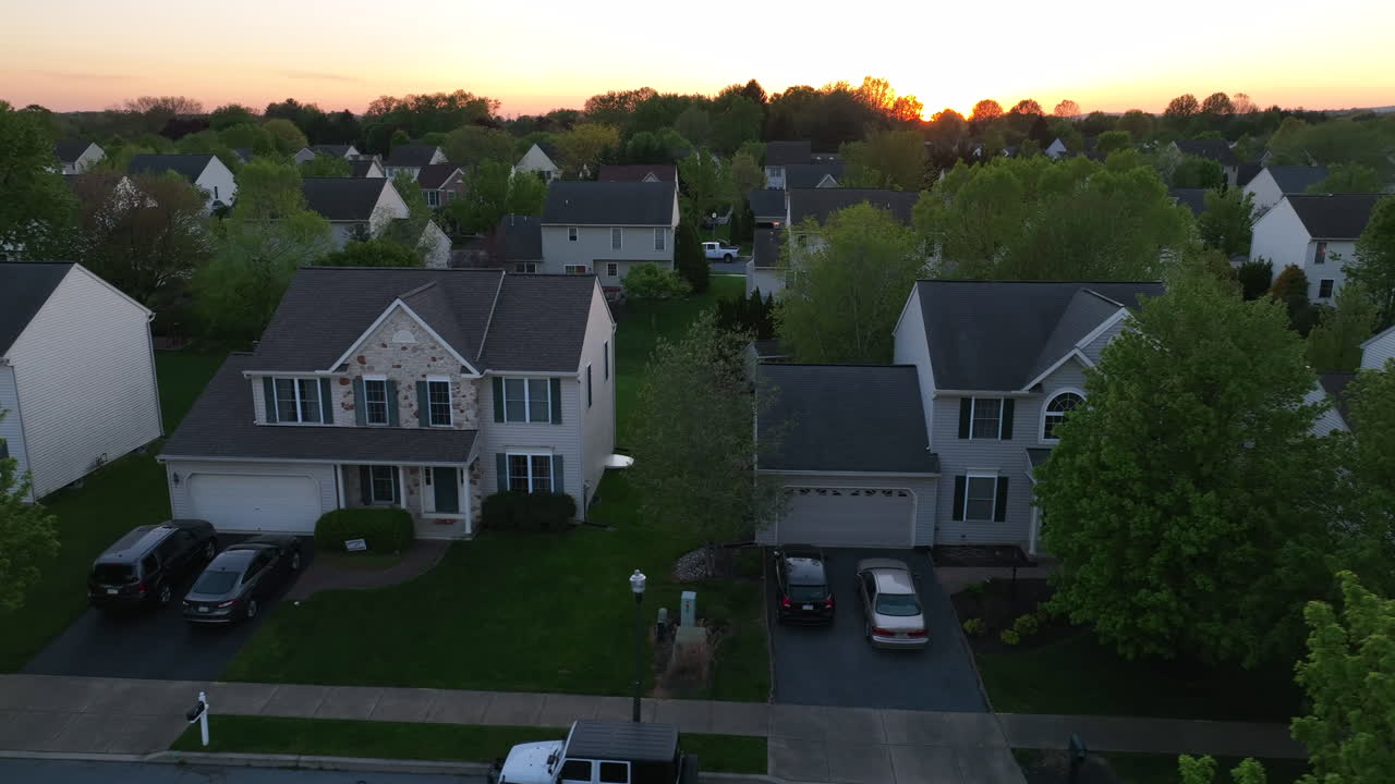 Houses in neighborhood at springtime. Aerial truck shot of homes during sunset. Establishing shot of new housing development in suburban America.