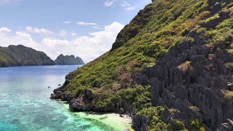 aerial view of tapiutan island, philippines featuring vibrant turquoise waters, rugged limestone cliffs, and dense tropical greenery beneath a sunny sky
