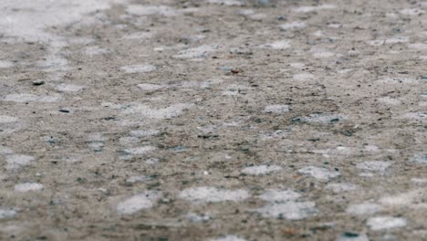 drops of rain fall to the pavement forming a puddle