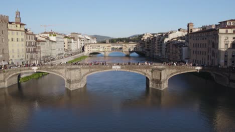 tourists walking over st trinity bridge, florence, italy