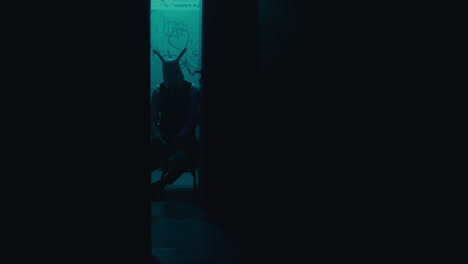 person in a rabbit mask sitting in a dark doorway