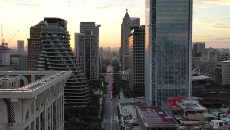 cinematic aerial dolly in shot, drone flying above songgao road with high-rise skyscrapers and apartment complex alongside at sunset in downtown xinyi district, taipei city, taiwan