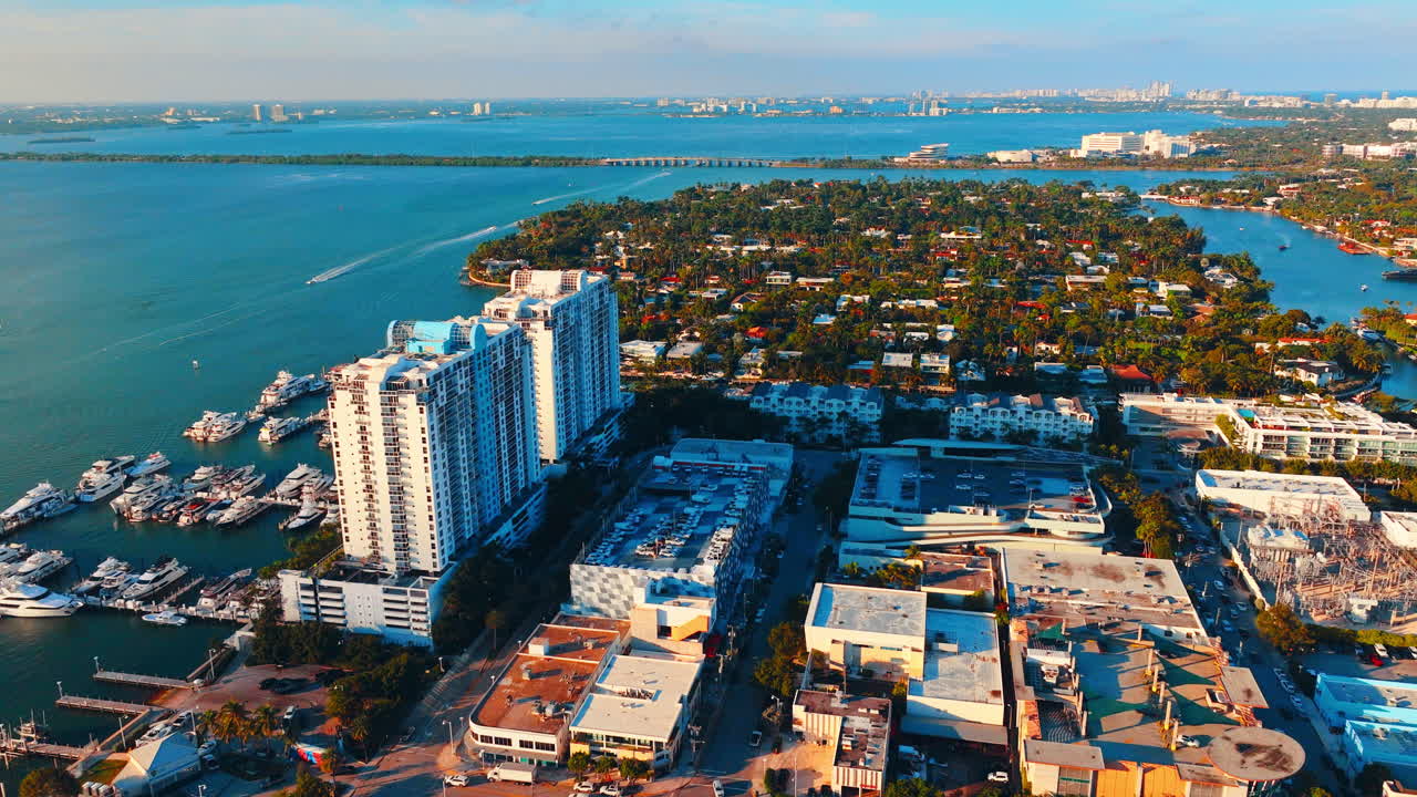 Torres residenciales blancas junto a un puerto deportivo para yates y agua turquesa bajo un cielo despejado. Vista aérea de edificios de la ciudad costera de Miami