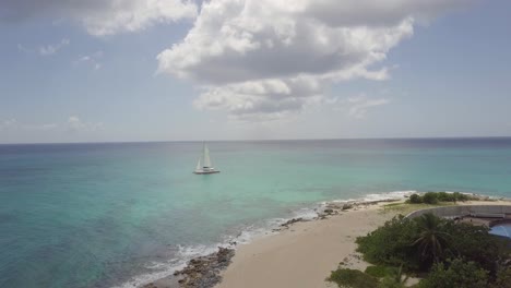 drone approaching small isolated sail boat on calm paradise tropical beach caribbean sea water in saint martin leeward islands