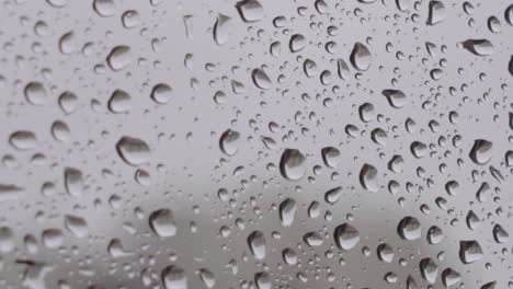 extreme closeup of large raindrops on window with grey background