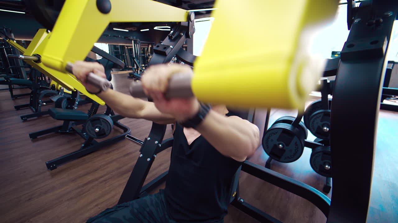 Muscular man exercising in gym. Athlete exercising using weight lifting machine to lose weight