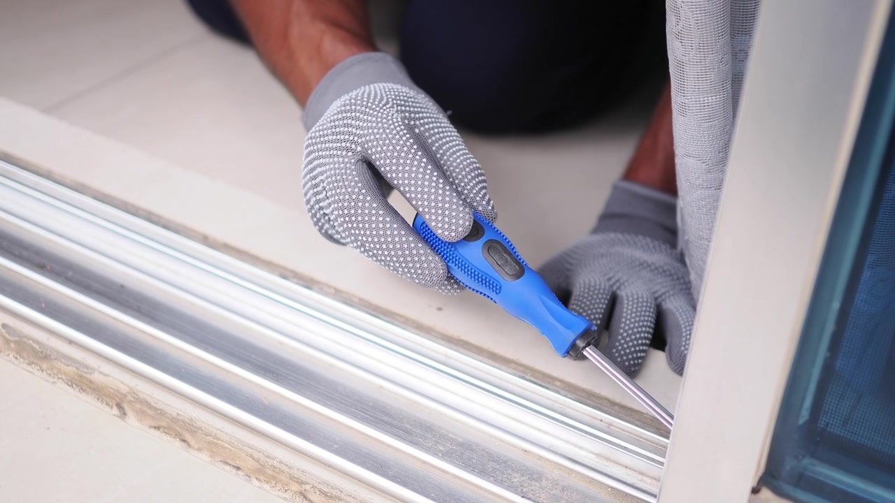 Handyman Using Screwdriver to Repair Sliding Door Track