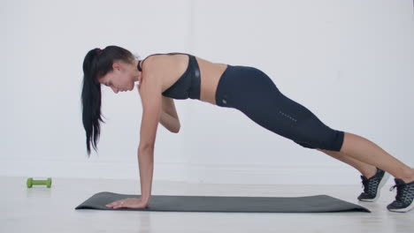 the girl is ferforming plank-exercise on the mat