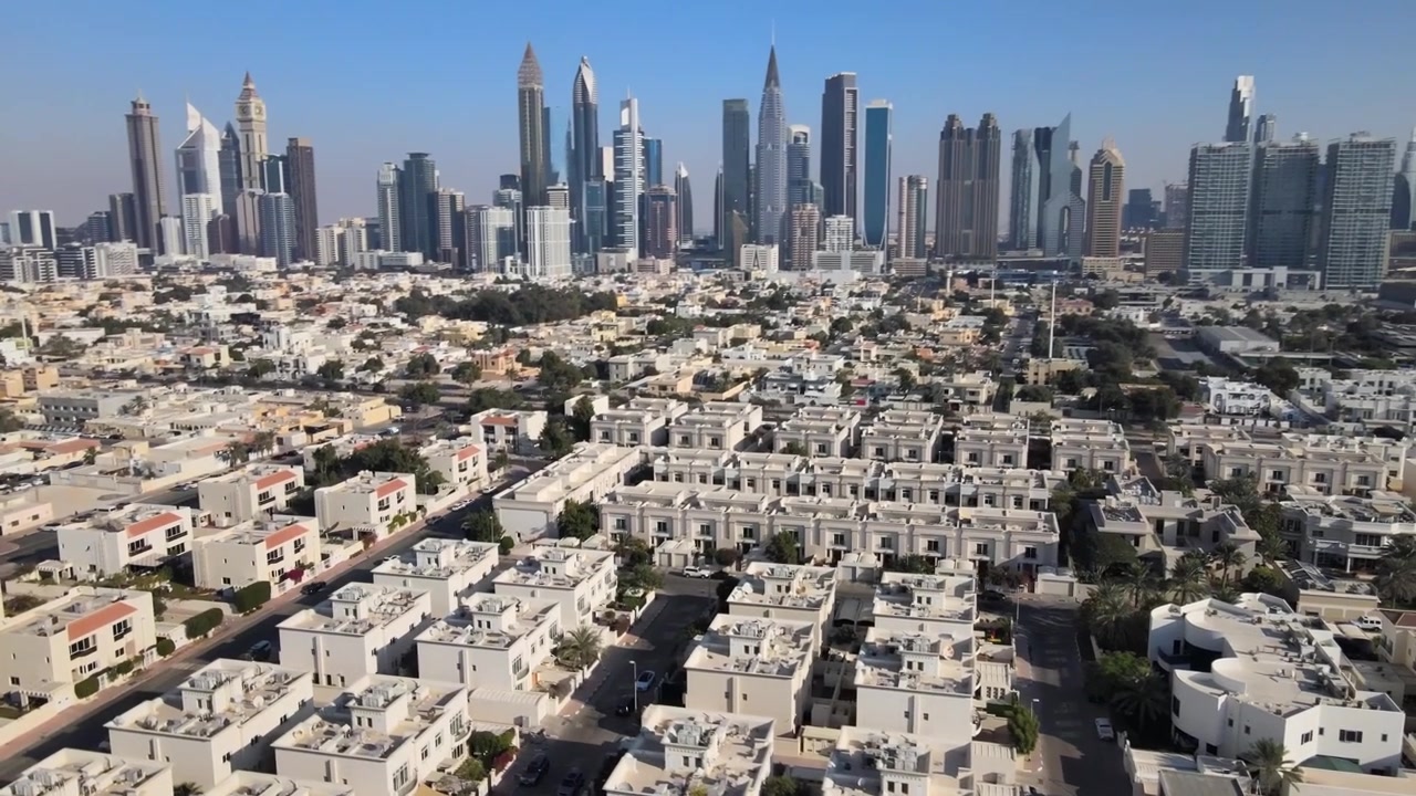 Veduta aerea di un quartiere di Dubai con lo skyline e la Torre Burj Khalifa sullo sfondo durante una giornata di sole - ripresa orbitante