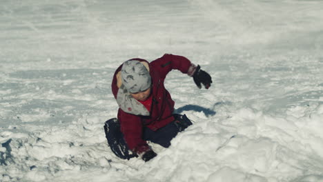 Energetic-Little-Boy-Digs-in-Snow-with-Hands-and-Sits-Back-to-Look-Around