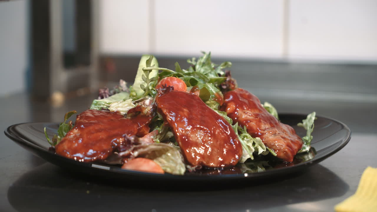 Chef is working on presenting the dish in the commercial kitchen. Warm salad with veal.