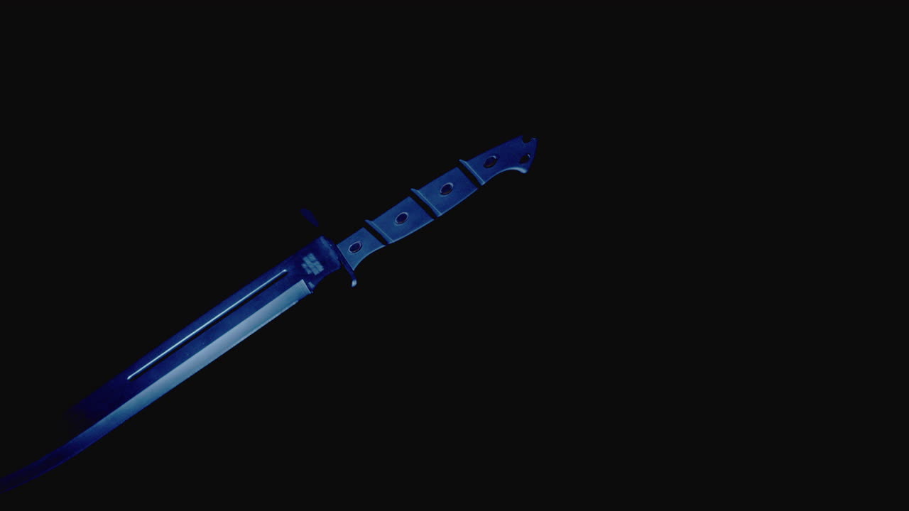 Knives on the dark background and in blinking red and blue light rotate in slowmotion